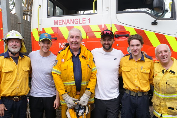 Tim Paine and Nathan Lyon pose for a photo with RFS firefighters in the Southern Highlands on Wednesday.
