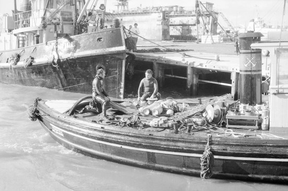 Divers return to port aboard the “Versatile” after rescue operations for the men on tug “Melbourne” were called off. 