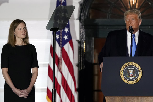 Amy Coney Barrett listens to US President Donald Trump at her Supreme Court swearing in ceremony at the White House on Monday night (Tuesday AEDT).