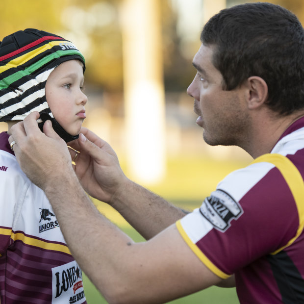 Father Sean Buchanan adjusts the headgear on his six-year-old son Beau, who plays for the Glenmore Park Brumbies in the Penrith Junior Rugby League.