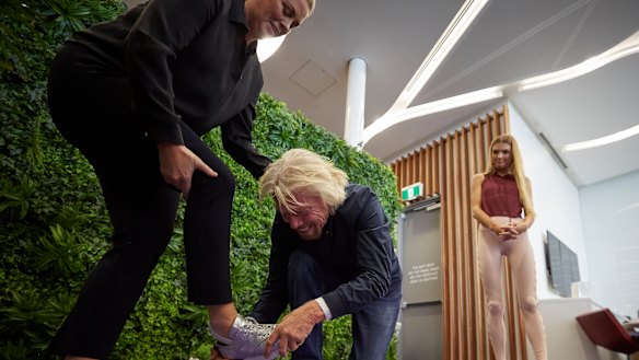 Ever the gentleman, Sir Richard Branson helping Samantha Armytage with her shoes in the Virgin Lounge on Thursday.