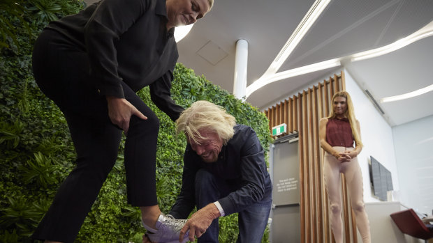 Ever the gentleman, Sir Richard Branson helping Samantha Armytage with her shoes in the Virgin Lounge on Thursday.