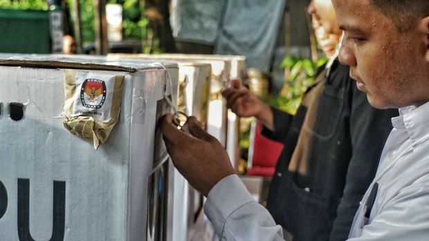 Party observers check a sealed ballot box before the start of voting at a South Jakarta polling station on Wednesday.