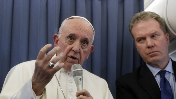 Pope Francis, flanked by Vatican spokesperson Greg Burke, listens to a journalist's question during a press conference aboard of the flight to Rome at the end of his two-day visit to Ireland.