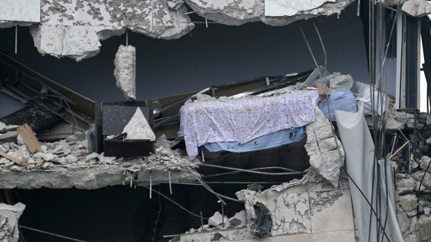 A bed dangles from the collapsed building.