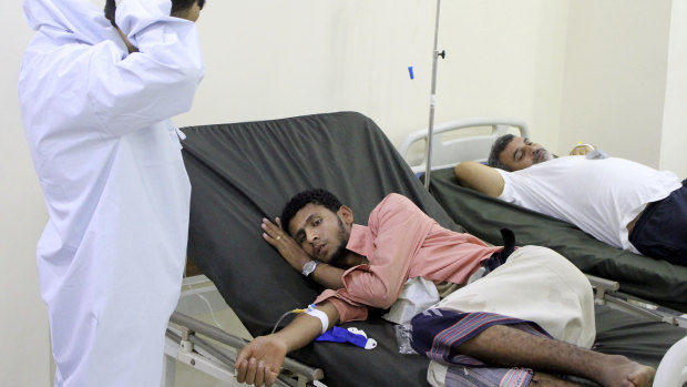 A Yemeni doctor talks to a patient receiving treatment and lying on a bed at a hospital in Aden, Yemen. 