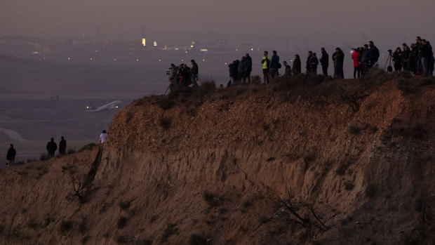 Members of the public and journalists stand on a hill to watch an emergency landing of the Air Canada flight in Madrid. 