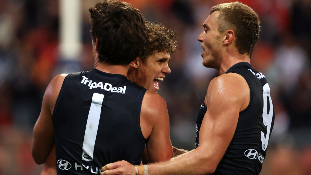 Charlie Curnow celebrates a goal with Jack Silvagni and skipper Patrick Cripps.