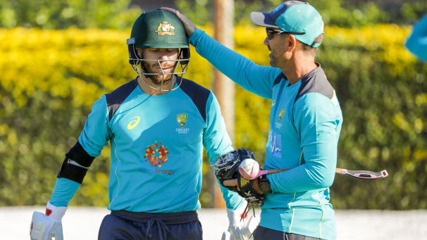 Australia coach Justin Langer pats David Warner on the helmet at training in Brisbane.
