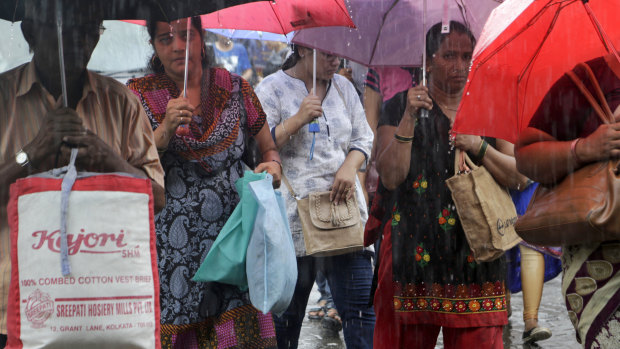 Shoppers carry non-plastic bags during rains at a market in Mumbai on Saturday.
