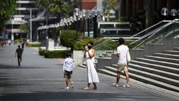 People wearing protective face masks walk along the Orchard Road shopping belt in Singapore.