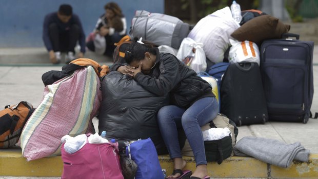 Carolina Torres, a Venezuelan woman who worked as a life insurance saleswoman in her home country, rests on her luggage in the border town of Tumbes, Peru.
