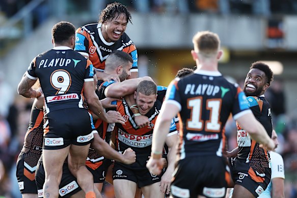 The Tigers celebrate with Adam Doueihi after his late field goal won the match against the Titans at Leichhardt Oval on Sunday.