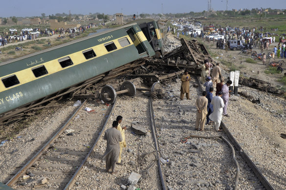 Residents examine damaged cars of a passenger train which was derailed near Nawabshah, Pakistan.