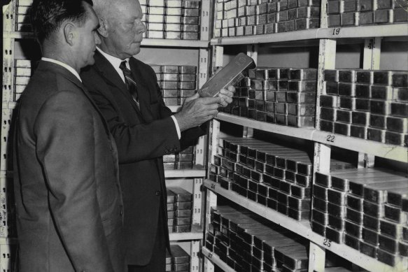 Mr. M.A. Aitken (left), internal audit officer, and Mr. T.W. Chaplin, chief cashier, handling a bar of gold worth £6,250 in the vaults of the Reserve Bank at Martin Place. December 22, 1964. 