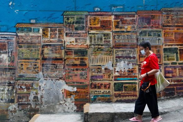 A woman walks past a fading mural that depicts traditional Hong Kong houses. 