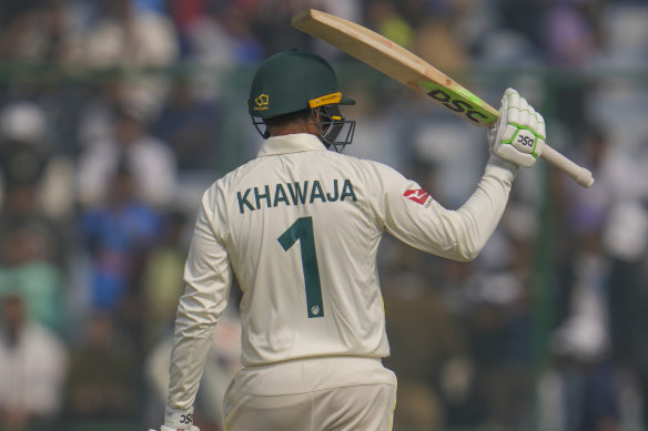 Usman Khawaja raises his bat to mark his half century.