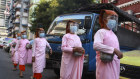 Buddhist nuns wearing face masks and shields to help curb the spread of the coronavirus walk to collect cash and rice from devotees on Wednesday.