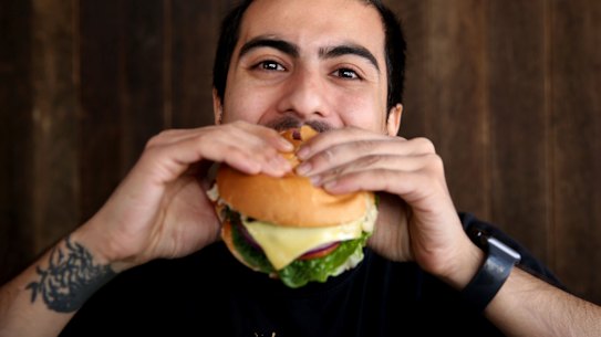 Surat Khadka bites into a meat-free, plant based, hamburger from Soul Burger.