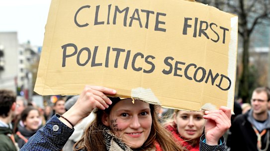 A demonstrator holds a placard which reads 'climate first, politics second' during a 'Claim the Climate' march in Brussels, on Sunday.