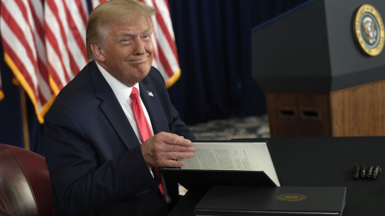President Donald Trump smiles as he is about to sign four executive orders during a news conference at the Trump National Golf Club in New Jersey on August 8.