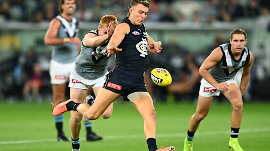 Patrick Cripps of the Blues kicks whilst being tackled by Willem Drew of the Power.