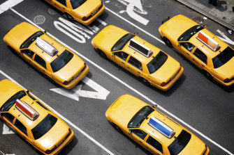 A fleet of yellow taxi cabs make their way down the street of Broadway in New York City.