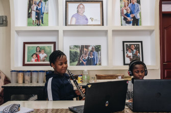 Verisiah Kambale, 11, who has continued her private school's classes online, and her younger brother Joseph Tayo Kambale use laptops at their home in Nairobi.