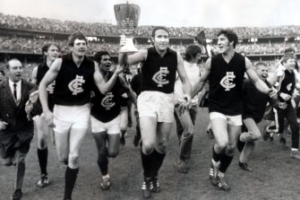 Carlton captain John Nicholls holds the premiership cup as Carlton laps the MCG.