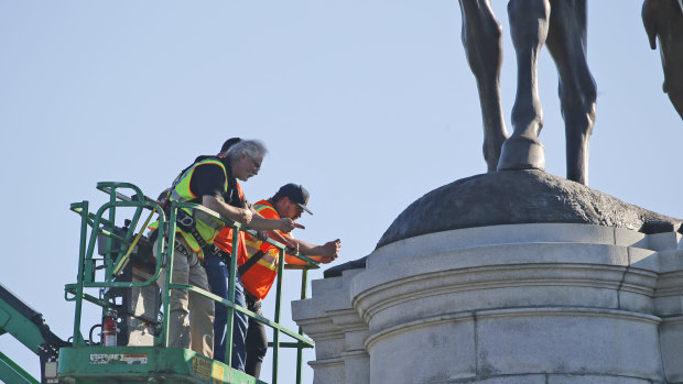 A crew from the Virginia Department of General Services inspects the base of the statue of Confederate General Robert E. Lee on Monument Avenue on Monday. 