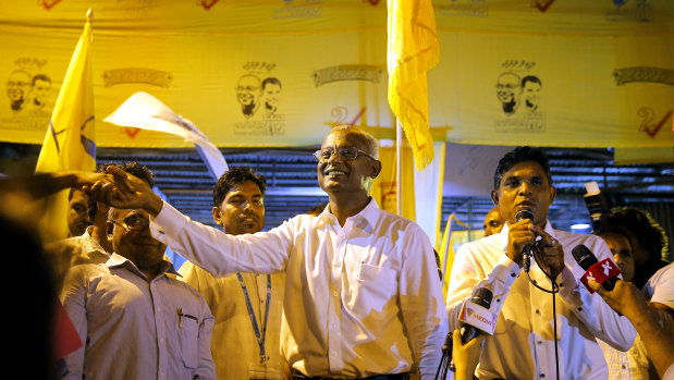 Maldives' opposition presidential candidate Ibrahim Mohamed Solih, centre, shakes hands with a supporter as his running mate, Faisal Naseem, right, addresses the gathering in Male, Maldives, on Monday.