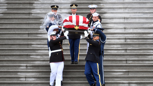 The casket of John McCain is being carried down the steps of the US Capitol last year. 