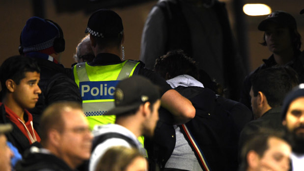 Police remove a member of the crowd at Marvel Stadium.