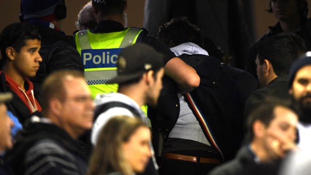 Police remove a member of the crowd at Marvel Stadium.