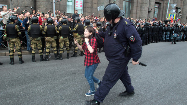 A Russian police officer detains a teenager during rally protesting retirement age hikes in St Petersburg, Russia.