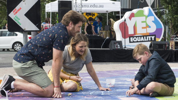 Daniel Little, Natalie Plummer, and Logan Little, 9, of Curtin take part in drawing with chalk on the rainbow roundabout.
