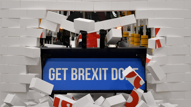 Prime Minister Boris Johnson drives a JCB through a symbolic wall. 