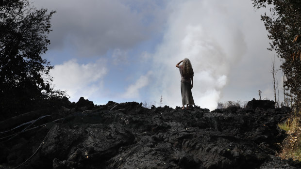 Hannique Ruder, a 65-year-old resident living in the Leilani Estates subdivision, stands on a mound of hardened lava near Pahoa, Hawaii on Friday.