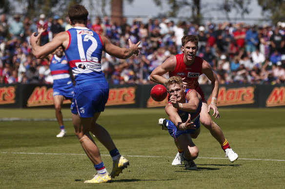 Adam Treloar gets a handball away.