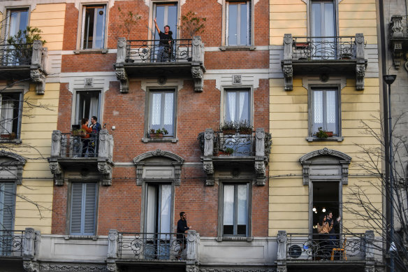 People in lockdown stand on their balconies in Milan, Italy.
