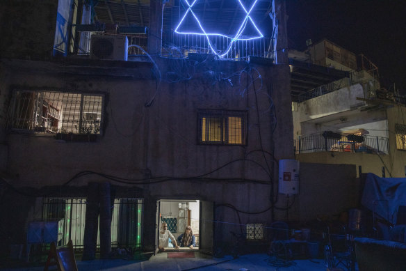 Nasser Rajabi and his mother, in the doorway below, share a house in East Jerusalem with Jewish settlers.