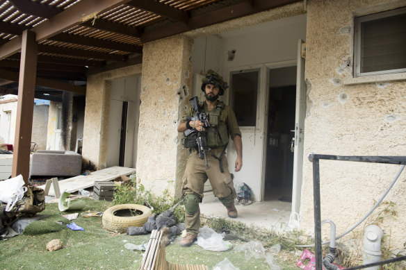 An Israeli soldier exits a destroyed house after an attack by Palestinian militants near the border with Gaza in Kfar Gaza, Israel. 
