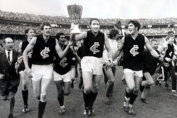 Carlton captain John Nicholls holds the premiership cup as Carlton laps the MCG.