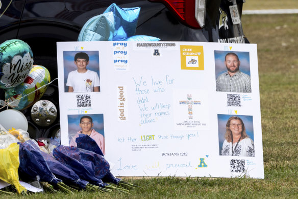 A poster with images of victims Christian Angulo, top left, Richard Aspinwall, top right, Mason Schermerhorn, bottom left, and Cristina Irimie is displayed at a memorial outside Apalachee High School on Friday.