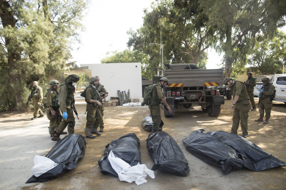 Israeli soldiers remove the bodies of civilians killed in an attack on a  kibbutz.