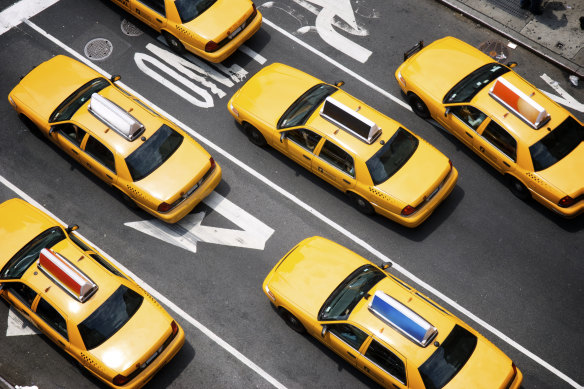 A fleet of yellow taxi cabs make their way down the street of Broadway in New York City.