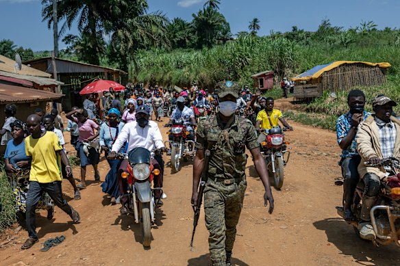A soldier escorts the crowd of people who had tried to retrieve the body of Reverend Sylvestre Atama, a popular and charismatic preacher who died of Ebola.