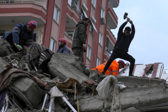 Emergency team members and others search for people in a destroyed building in Adana, Turkey.