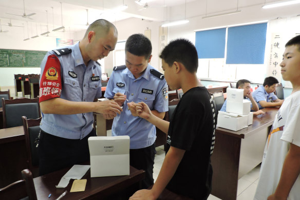 Police officers from the Jiufeng police station in Shaanxi Province collect DNA samples from a boy. 