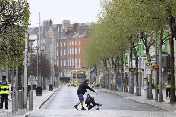 A man pushes a pram across an almost deserted O'Connell Street in Dublin's city centre.